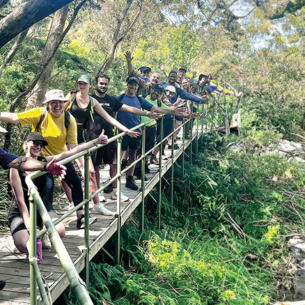 Large group of people standing on a narrow wooden bridge in a national park during a Mission Australia fundraising hiking event.