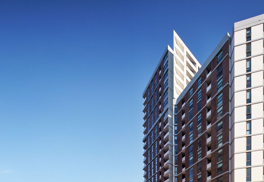 High-rise apartment buildings at Midtown Macquarie Park in Sydney, photographed from street level against a clear blue sky.