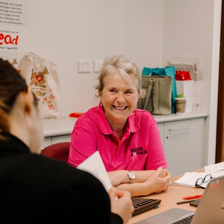 A Mission Australia case worker with a lovely warm smile, speaks to a client in her office.