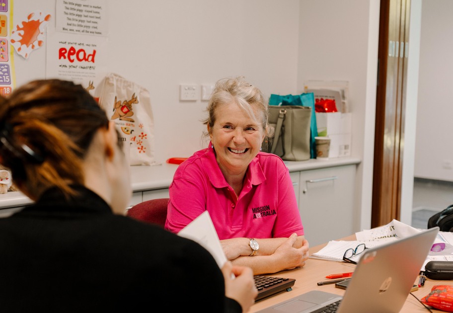 A Mission Australia case worker with a lovely warm smile, speaks to a client in her office.