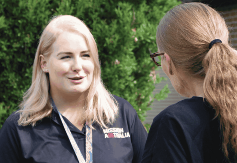 Two Mission Australia staff members talking together outdoors.